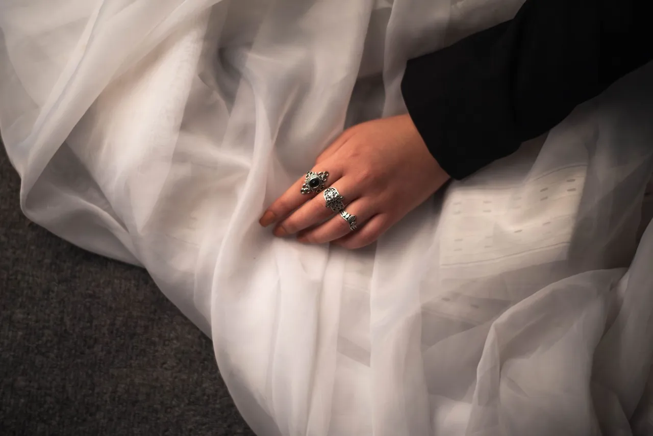 Silver rings worn with soft ivory fabric and a tailored black sleeve
